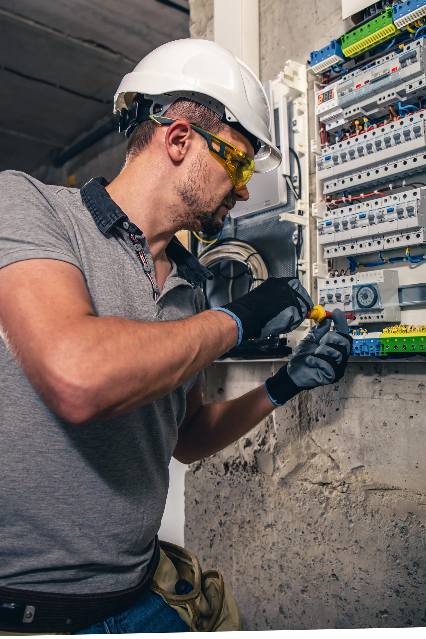 Man, an electrical technician working in a switchboard with fuses.